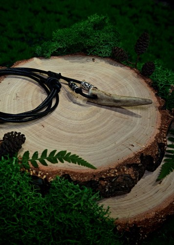 Ręcznie wykonany wisiorek z naturalnego fragmentu poroża sarny. Smukły, lekko zakrzywiony kształt oraz jasna, delikatnie przebarwiona powierzchnia nadają mu surowy, leśny charakter.