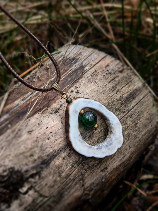 Ręcznie wykonany wisiorek z naturalnego poroża jelenia, starannie wycinany i szlifowany w organiczny, owalny kształt.