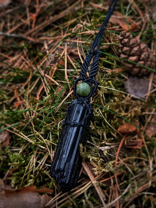 ęcznie wykonany wisiorek z naturalnym czarnym turmalinem, opleciony czarnym sznurkiem w stylu makramy. Podłużny, surowy kamień o głębokiej czerni pięknie łączy się z ciemną plecionką