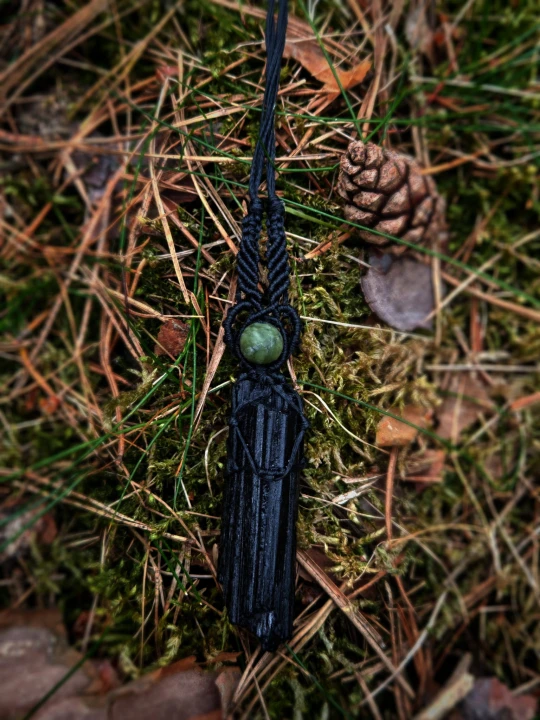 ęcznie wykonany wisiorek z naturalnym czarnym turmalinem, opleciony czarnym sznurkiem w stylu makramy. Podłużny, surowy kamień o głębokiej czerni pięknie łączy się z ciemną plecionką